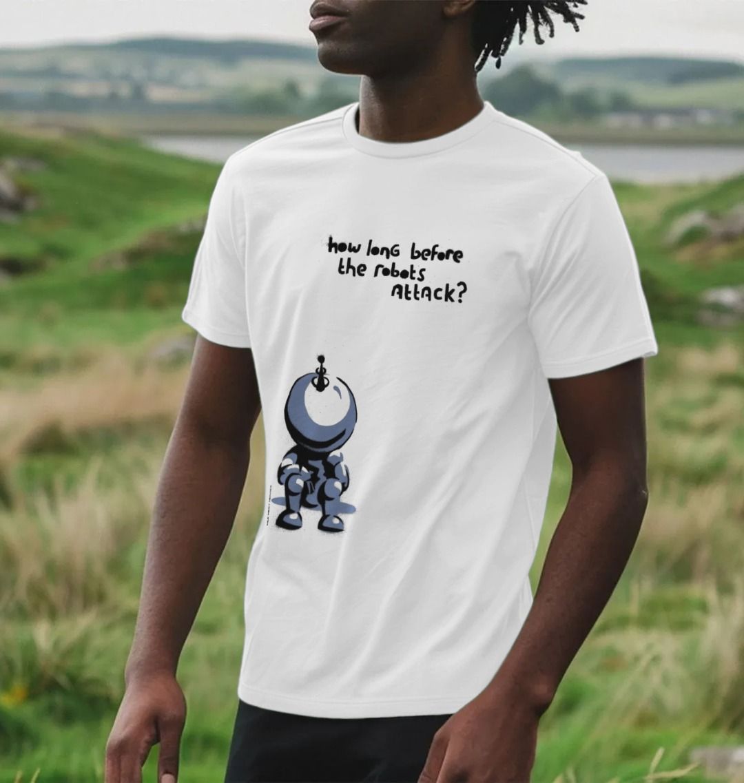 Man stood in the countryside near the sea wearing a White  How Long Before The Robots Attack Graphic T-Shirt